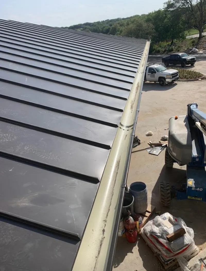 Standing seam panel and gutter detail on a metal roofing jobsite in Raymond